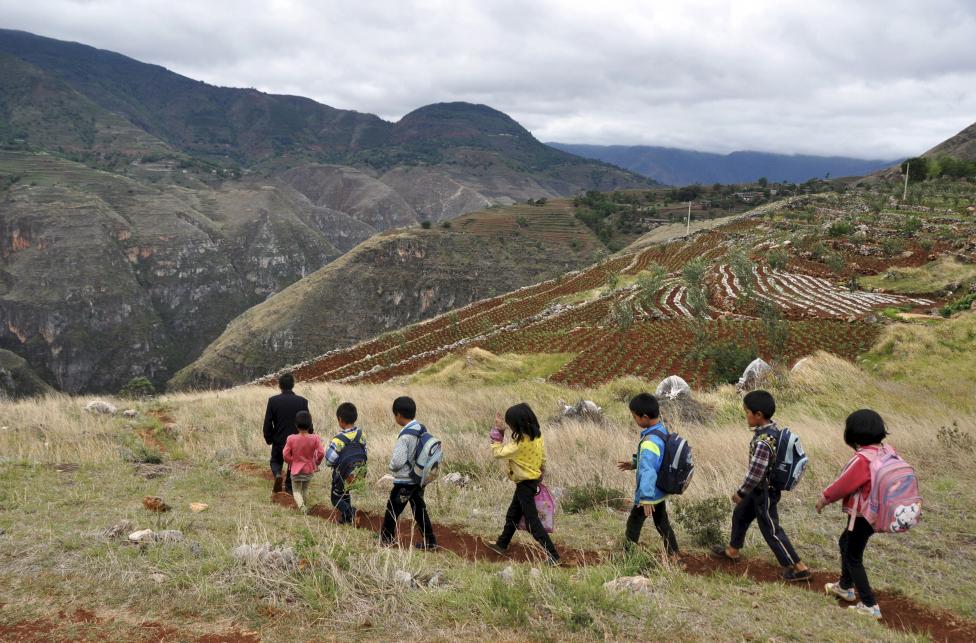 Xie Bihua (L), a 47-year-old teacher of a rural primary school located at the mountainous area, leads on a small dirt road as he walks with his students after school, in Weining Yi, Hui, and Miao Autonomous County, Guizhou province, China, May 28, 2015.  REUTERS/Stringer